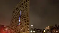 Sebuah proyeksi Menara Eiffel ditampilkan di sisi bangunan Flatiron New York City, Rabu (18/11). Gambar yang menampilkan tulisan She is tossed by waves but does not sink itu bentuk solidaritas terkait serangan teror Paris. (Andrew Burton/Getty Images/AFP)