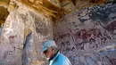 Arkeolog Jose Berenguer menunjukkan lukisan hewan llama di dinding batu cadas Gua Taira Calama, Chile, Minggu (21/7). Para penggembala meninggalkan sejumlah lukisan hampir tiga milenium lalu. (Martin Bernetti/AFP)