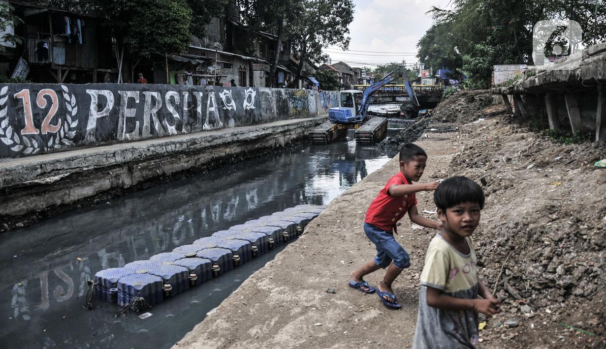 Anak-anak bermain di sekitar Kali Sentiong, Kecamatan Johar Baru, Rabu (22/9/2021). Pengerukan lumpur ini merupakan bagian dari program normalisasi guna memperdalam aliran Kali Sentiong. (merdeka.com/Iqbal S. Nugroho)