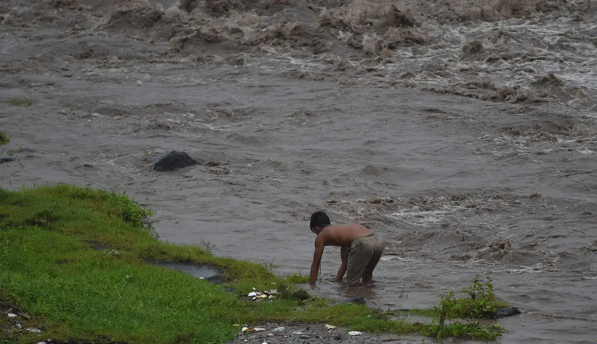 Warga mencari ikan di sepanjang sungai dekat gunung berapi Mayon di kota Daraga, provinsi Albay, selatan Manila (27/1). Akibat hujan deras, jutaan ton abu dan batu dari gunung mayon mengalir kesungai. (AFP Photo/Ted Aljibe)