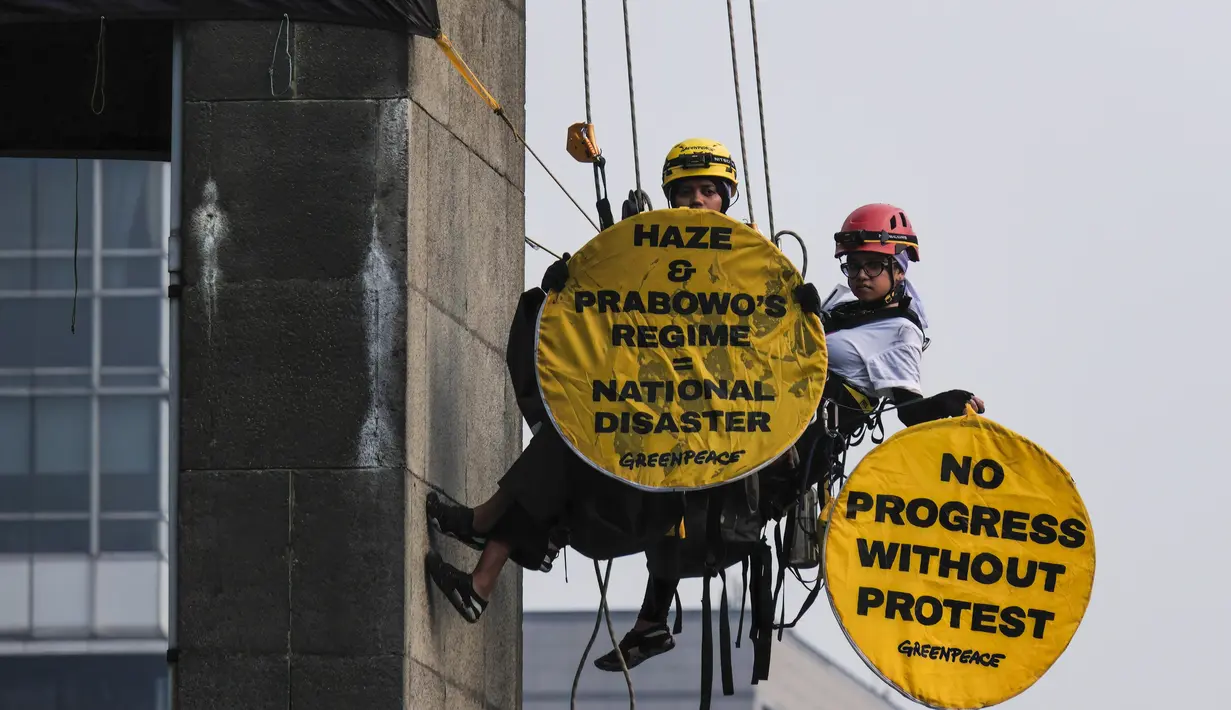 Aktivis Greenpeace Indonesia bergelantungan di Patung Selamat Datang sambil membentangkan poster berisi pesan protes di kawasan Bundaran Hotel Indonesia, Jakarta, Selasa (20/10/2026). Aksi tersebut digelar bertepatan dengan dua tahun pelantikan Presiden Prabowo Subianto. Para aktivis mendesak pemerintah mengambil langkah untuk mengatasi krisis iklim yang kian memburuk dan kenaikan biaya hidup. (BAY ISMOYO/AFP)