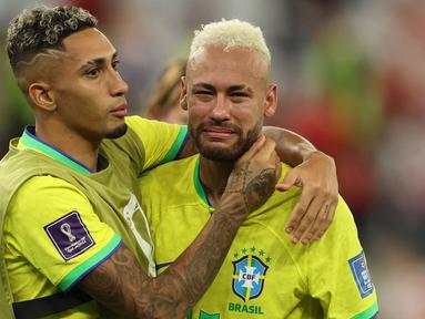Pemain Brasil, Neymar (kanan) dihibur oleh rekannnya, Raphinha setelah tim mereka kalah dari Kroasia saat laga perempat final Piala Dunia Qatar 2022 yang berlangsung di Education City Stadium, Al-Rayyan, Jumat (09/12/2022) waktu setempat. Brasil kalah 2-4 dari Kroasia saat babak adu penalti. (AFP/Adrian Dennis)