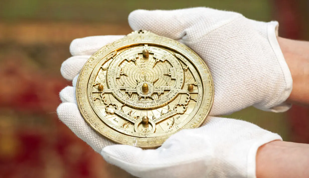 Karyawan rumah lelang Sotheby memegang astrolab abad ke-14, instrumen astronomi yang dipakai astronom untuk menghitung posisi matahari dan bintang, senilai 600.000-800.000 pound sterling jelang Arts of the Islamic World dan India di London, Inggris, Senin (29/3/2021). (Dominic Lipinski/PA via AP)