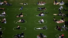 Orang-orang berusaha menjaga jarak dalam lingkaran putih saat bersantai di Domino Park, Brooklyn di Kota New York, Minggu (17/5/2020). Pengunjung taman berjemur dengan tetap menerapkan protokol penularan coorna Covid-19. (Photo by Johannes EISELE / AFP)