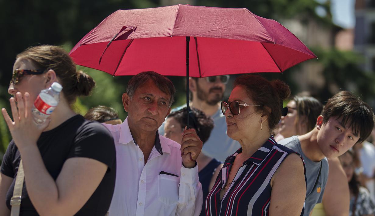 Pasangan berlindung dari terik matahari saat musim panas di Madrid, Spanyol, Sabtu, 8 Juli 2023. (AP Photo/Manu Fernandez)