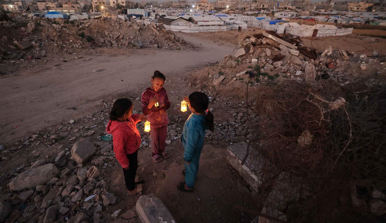 Kehangatan suasana jelang buan suci Ramadan begitu terasa di tengah hamparan tenda pengungsi dan kondisi yang serba terbatas. Tampak dalam foto, beberapa pengungsi muda Palestina bermain di reruntuhan bangunan yang hancur di kamp pengungsi Bureij di Jalur Gaza tengah pada 15 Februari 2026. (Eyad Baba/AFP)