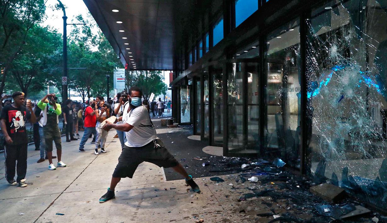 Pengunjuk rasa menghancurkan jendela di kantor pusat CNN di Atlanta, Georgia, Jumat (29/5/2020). Massa yang mengecam kematian George Floyd (46) oleh polisi melakukan vandalisme dan perusakan gedung CNN pusat. (Alyssa Pointer/Atlanta Journal-Constitution via AP)
