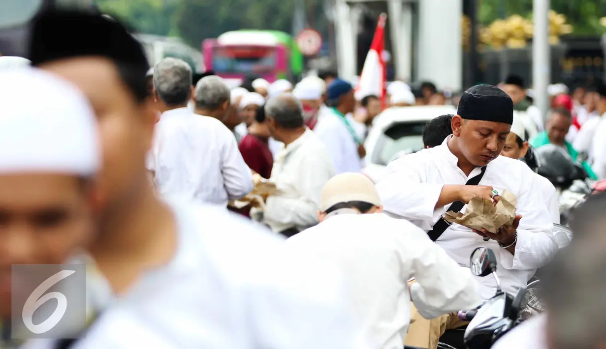 Sejumlah massa aksi makan siang sebelum memulai aksi di Medan Merdeka Timur, Jakarta, Jumat (4/11). Massa melakukan aksi di depan Istana Negara menuntut penegakan hukum kasus dugaan penistaan agama. (Liputan6.com/Faizal Fanani)