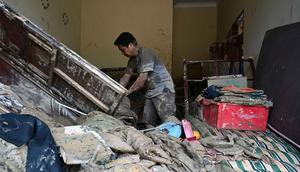 Desa Garoga dilaporkan "hilang" dan berganti menjadi hamparan lumpur, batu, serta sampah potongan dan batang kayu pohon. Tampak dalam foto, seorang warga mengumpulkan barang-barangnya dari rumahnya yang rusak akibat banjir bandang di Garoga, Provinsi Sumatera Utara, pada Kamis 4 Desember 2025. (YT HARIONO/AFP)