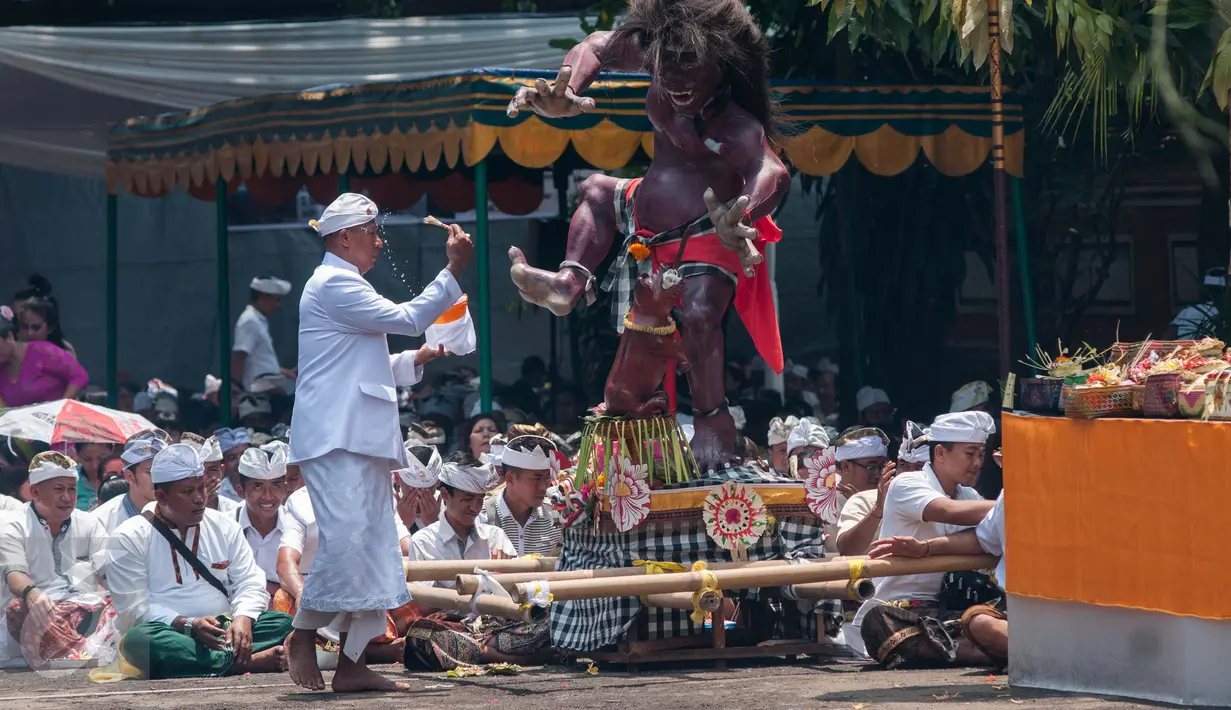 Pemangku menyipratkan air suci pada patung ogoh-ogoh dalam prosesi Tawur Agung Kesanga di Pura Aditya Jaya, Jakarta, Senin (27/3). Kegiatan Tawur Agung Kesanga merupakan salah satu dari empat ritual utama perayaan Nyepi. (Liputan6.com/Gempur M Surya)