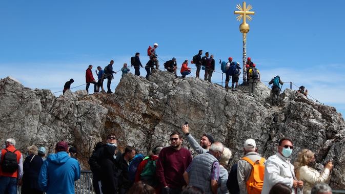 Orang-orang mengantre untuk mencapai puncak salib di puncak gunung tertinggi Jerman, Zugspitze, dekat Garmisch-Partenkirchen, Jerman pada 19 Agustus 2020. Setiap tahunnya gunung dengan ketinggian 2.962 meter tersebut membuat sekitar setengah juta pengunjung terpesona. (AP Photo/Matthias Schrader)