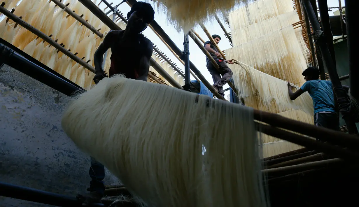 Pekerja India menggantung helai bihun untuk dikeringkan di sebuah pabrik di Ahmadabad pada 16 Mei 2019. Bihun sangat diminati di kalangan muslim India karena merupakan menu favorit yang kerap disuguhkan saat berbuka puasa bersama dengan buah-buahan manis. (AP Photo/Ajit Solanki)