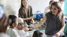Artis Jessica Iskandar mengajak bicara anak-anak rumah singgah Yayasan Bina Anak Pertiwi, Jakarta, Selasa (12/6). Jessica bercerita bahwa dirinya telah mengadopsi tiga anak berkebutuhan khusus dari yayasan yang berbeda. (Liputan6.com/Faizal Fanani)