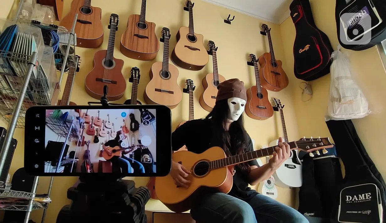 Pemilik showroom dan bengkel Gitar "music666", Ridwan dan Rudi mendemonstrasikan gitar yang akan dijual secara daring di Ciledug, Tangerang, Rabu (22/7/2020). Pemerintah menargetkan 10 juta usaha mikro kecil menengah (UMKM) pada tahun ini terhubung dengan platform digital (Liputan6.com/Angga Yuniar)