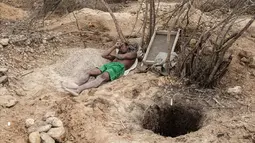 Seorang penambang beristirahat di sebelah lubang tambang safir di Sakaraha, Madagaskar. Pulau yang terletak di Samudra Hindia itu sudah menjadi salah satu produsen tambang batu mulia safir terbesar di dunia. (AFP Photo/Gianluigi Guercia)