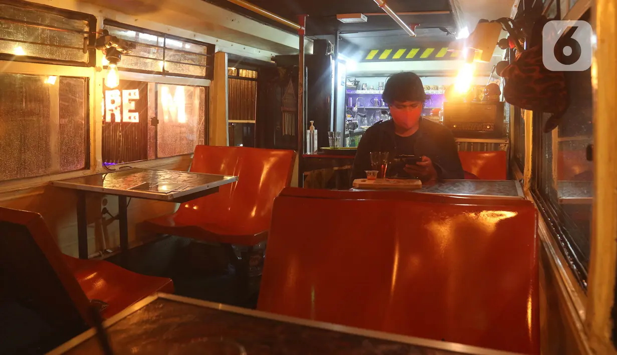 Pengunjung menyantap makanan di kafe yang menggunakan angkutan metromini di Bekasi, Jawa Barat, Kamis (15/4/2021). Kafe ini berinovasi di tengah pandemi COVID-19 dengan menggunakan armada metromini yang sudah tidak terpakai sebagai tempat makan pengunjung. (Liputan6.com/Herman Zakharia)