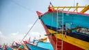 Berhentinya ribuan kapal berdampak pada sepinya aktivitas perdagangan di Tempat Pelelangan Ikan (TPI). Tampak dalam foto, seorang pria mengecat ulang perahu nelayan sementara kapal-kapal lain tetap berlabuh di Pelabuhan Juwana, Jawa Tengah, Rabu 6 Mei 2026. (Devi RAHMAN/AFP)