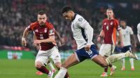 Pemain Inggris, Jude Bellingham (kanan), melepaskan tembakan ke gawang Latvia pada Kualifikasi Piala Dunia 2026 di Stadion Wembley, Selasa (25/3/2025) dini hari WIB. Inggris menang 2-0. (Glyn KIRK / AFP)