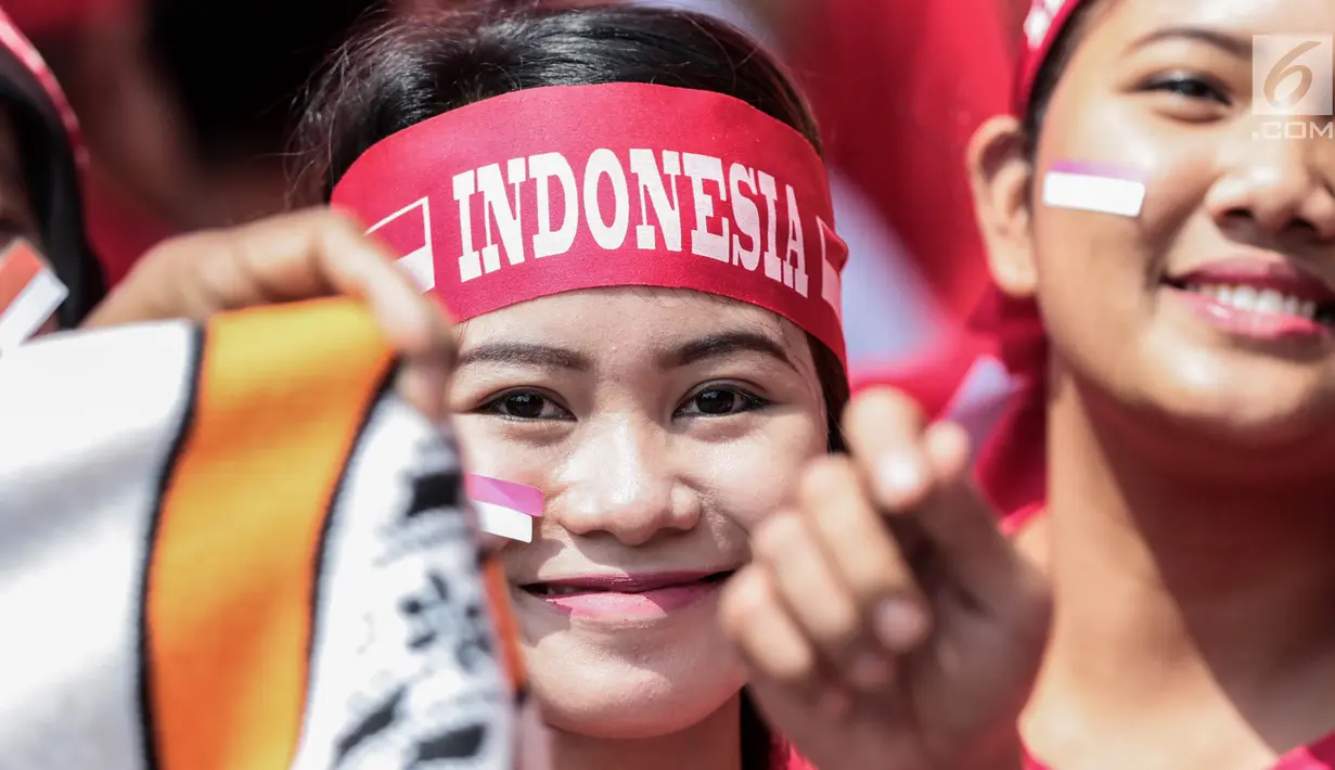 Seorang suporter menempelkan pipinya dengan stiker bendera Merah Putih untuk mendukung Timnas Indonesia U-22 pada laga lanjutan grup B SEA Games 2017 melawan Timor Leste, Minggu (20/8). Indonesia menang 1-0 atas Timor Leste. (Liputan6.com/Faizal Fanani)