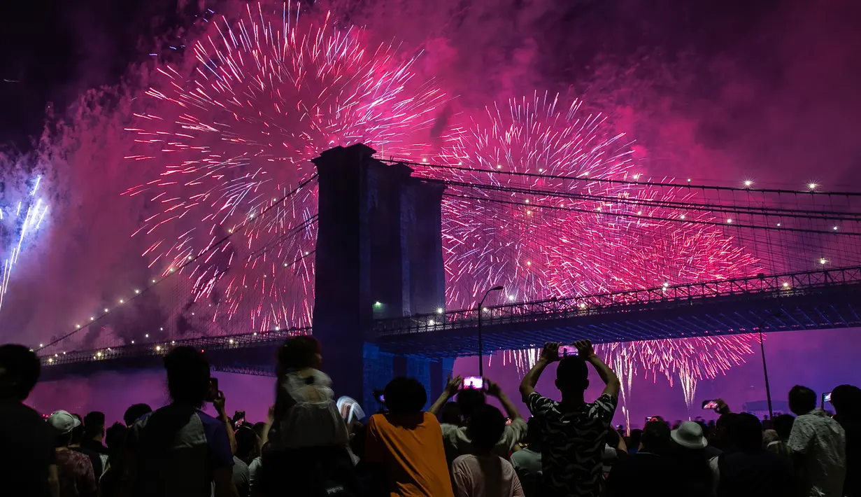 Orang-orang menyaksikan pertunjukkan kembang api di sisi timur Manhattan selama perayaan Hari Kemerdekaan Amerika Serikat atau yang dikenal sebagai Fourth of July di New York, Kamis (4/7/2019). Di Amerika Serikat sendiri, 4 Juli ditetapkan sebagai hari libur nasional. (AP Photo/Jeenah Moon)