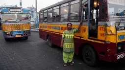 Pratima Poddar berpose di samping bus saat menunggu penumpang di Kolkata, India (8/3). Pratima Poddar 42 tahun merupakan satu-satunya sopir bus umum perempuan di Kolkata. (AFP Photo/Dibyangshu Sarkar)