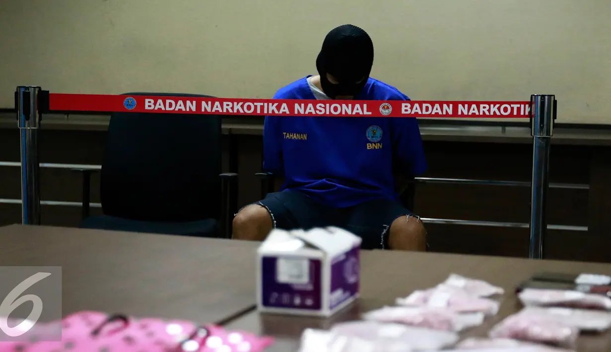Tersangka AR yang menjadi kurir dihadirkan dalam rilis di kantor BNN, Jakarta, Selasa (27/10/2015). BNN mengamankan empat tersangka kasus narkoba dengan barang bukti 1000 butir pil ekstasi, dua diantaranya merupakan oknum TNI. (Liputan6.com/Yoppy Renato)