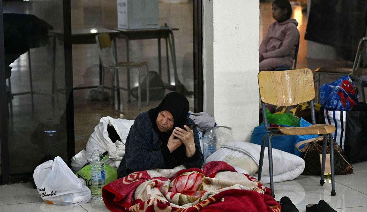 Hingga Kamis 5 Maret 2026, secara nasional, lebih dari 84.000 orang tercatat berada di 400 lokasi penampungan kolektif. Tampak dalam foto, seorang wanita mendengarkan teleponnya di dalam sebuah sekolah yang diubah menjadi tempat penampungan bagi para pengungsi di kota Dekwaneh, Lebanon, utara Beirut, pada Kamis 5 Maret 2026. (Joseph EID/AFP)