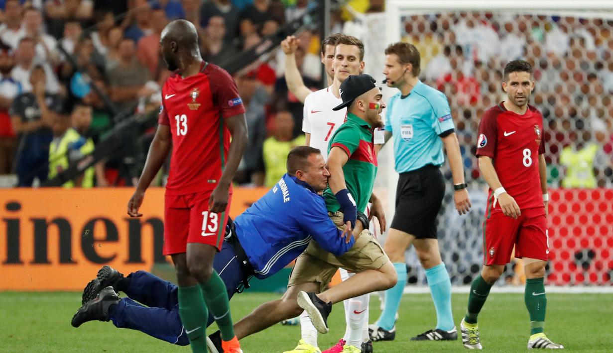 Seorang petugas menangkap suporter Portugal yang memasuki lapangan pada laga perempat final Piala Eropa 2016 di Stade Velodrome, Marseille, Jumat (1/7/2016) dini hari WIB. (Reuters/Yves Herman)