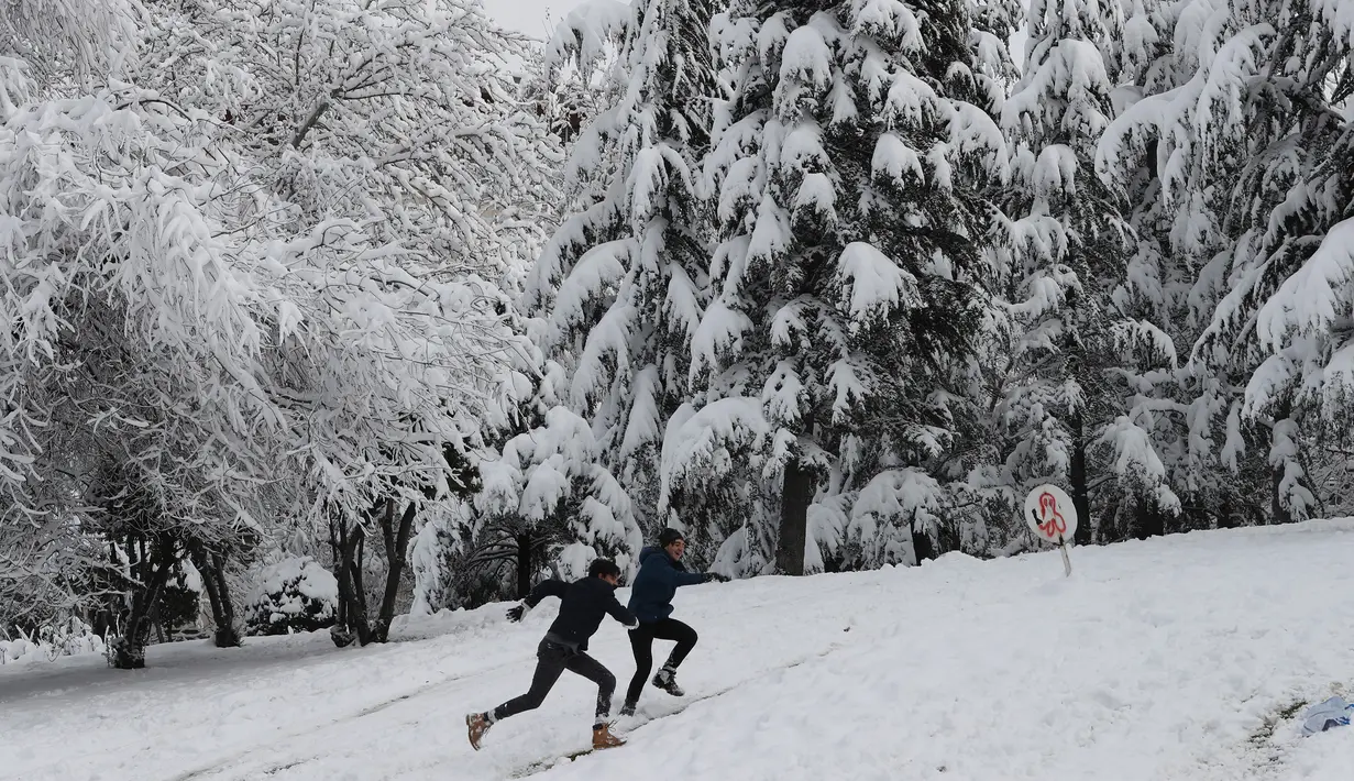 Anak-anak muda berlari menaiki bukit yang tertutup salju di sebuah taman di Ankara, Turki (26/12). AFP Photo/Adem Altan)