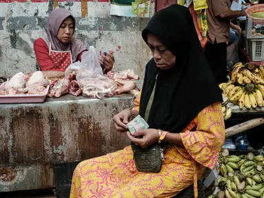 Seorang wanita menghitung uang kertas untuk membayar pembelian daging ayam di sebuah warung pinggir jalan di Jakarta pada Sabtu 8 November 2025. Pemerintah berupaya menjaga momentum agar rata-rata pertumbuhan ekonomi tahun ini bisa mencapai 5,2 persen. (YASUYOSHI CHIBA/AFP)