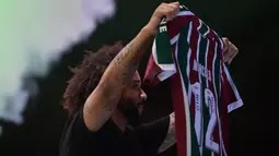 Marcelo menunjukkan baju dan nomor punggung yang akan ia gunakan saat perkenalan pemain baru Fluminense di Stadion Maracana, Rio de Janeiro, Brasil, Sabtu (11/03/2023) WIB. Mantan pemain Real Madrid tersebut bergabung hingga Desember 2024. (AFP/Carl De Souza)