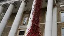 Anna Wigley mendongak ke arah karya seni bunga poppy bertajuk 'Weeping Window' di The Imperial War Museum, London, Kamis (4/10). Barisan bunga poppy itu tampak seperti darah yang mengalir dari bagian atas kastil. (AP Photo/Kirsty Wigglesworth)