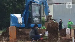 Aktivitas alat berat jenis eksavator membantu proses penggalian makam jenazah dengan protokol COVID-19 di area khusus TPU Srengseng Sawah, Jakarta, Kamis (14/1/2021). Pada Selasa (12/1) lalu, 47 jenazah dimakamkan dengan protokol COVID-19 di TPU Srengseng Sawah. (Liputan6.com/Helmi Fithriansyah)