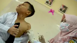 Ekspresi siswa MIN Ulee Kareng saat mendapat vaksinasi anti virus difteri di Banda Aceh, Aceh, Selasa (20/2). Maraknya kasus difteri belakangan ini membuat Kemenkes menginstruksikan pemberian vaksin untuk usia 1 hingga 19 tahun. (CHAIDEER MAHYUDDIN/AFP)