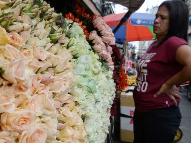 Seorang pembeli melihat bunga mawar yang dijajakan di sebuah kios sehari sebelum Valentine Day di Manila, Filipina, Rabu (13/2). Sudah tradisi di seluruh dunia, setiap hari valentine identik dengan pemberian bunga atau coklat. (TED ALJIBE/AFP)