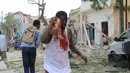 Seorang pria terluka akibat serangan bom mobil yang dilancarkan kelompok Alshabaab kepada sebuah hotel di di Mogadishu, Somalia, Rabu (25/1). Setidaknya 13 orang dilaporkan tewas dan puluhan lainnya terluka dalam kejadian ini. (AP Photo)