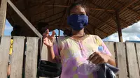 Seorang penyintas gempa Palu memakai dan menunjukkan masker gratis yang diterimanya dari komunitas Koplak, komunitas perantau Jawa yang sedang dan pernah bekerja di Palu, Jumat (10/4/2020). (Foto: Liputan6.com, Heri Susanto).