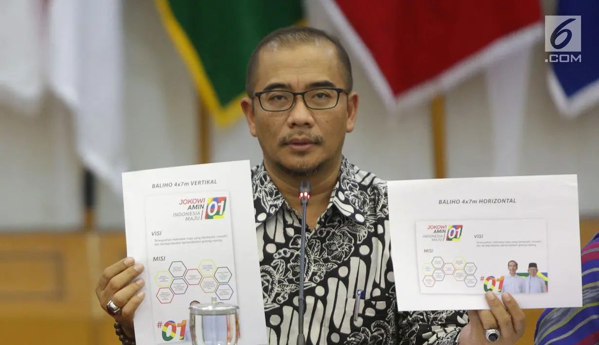 Komisioner KPU Hasyim Asy'ari menunjukkan desain pasangan capres nomor urut 01 saat rapat di Gedung KPU, Jakarta, Senin (29/10). Rapat membahas Penyampaian dan Penetapan Desain Alat Peraga Kampanye (APK). (Liputan6.com/Angga Yuniar)