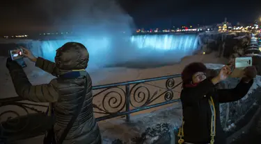 Dua oranga turis selfie di depan Air Terjun Niagara, Ontario, Kanada, Senin (9/1). Topan besar menerjang pantai timur Amerika Serikat pada 5 Januari lalu. (Geoff Robins/AFP)