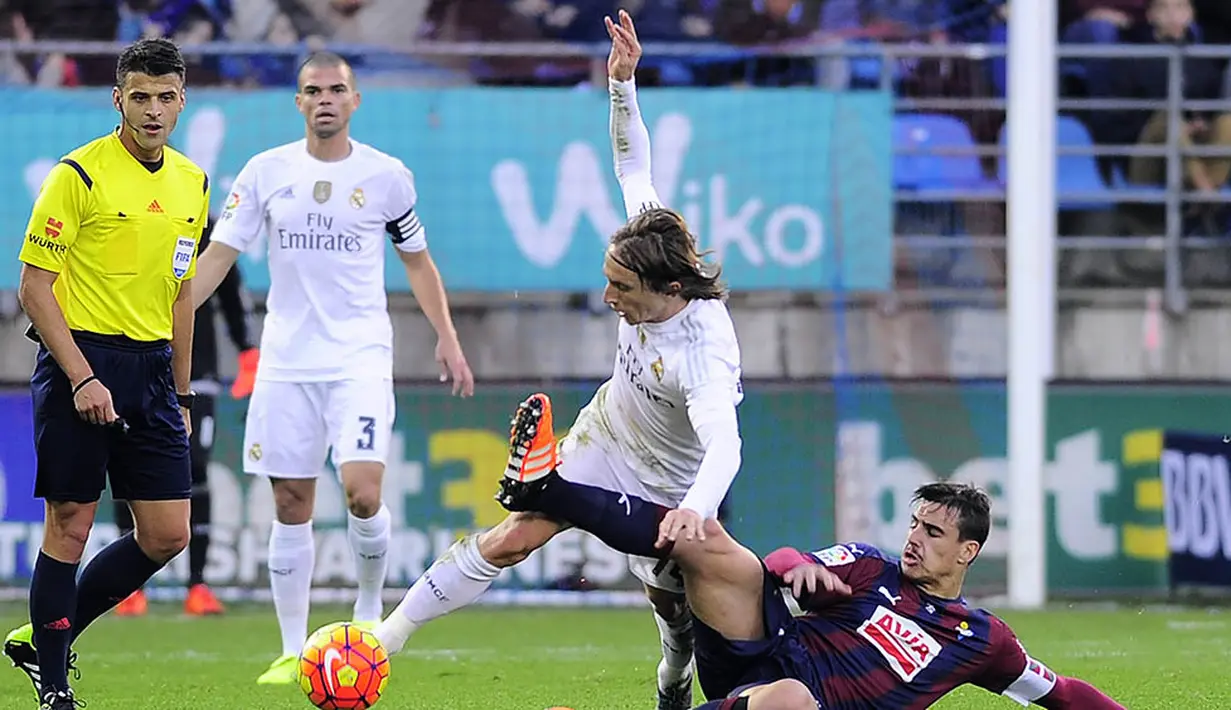 Gelandang Real Madrid, Luka Modric, berusaha menghindari tekel pemain Eibar, Daniel Garcia pada laga Liga Spanyol di Estadio Municipal de Ipurua, Spanyol, Minggu (29/11/2015). (AFP Photo/Ander Gillenea)