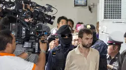 Petugas menggiring tersangka yang terlihat tegang ke dalam Pengadilan Bangkok, Thailand, Sabtu (5/9/2015). Tim forensik gagal menemukan kaitan pemboman Bangkok dengan dua pelaku serangan mematikan di Kuil Erawan, Thailand. (REUTERS/Athit Perawongmetha)