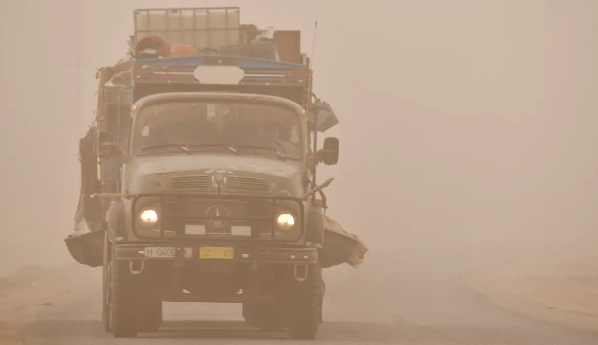 <p>Sebuah truk melaju melalui badai pasir Musim Semi di kota Nasiriyah, di provinsi Dhi Qar, Irak selatan (5/5/2022). Irak kembali diselimuti lapisan jingga tebal karena mengalami serangkaian badai debu terbaru yang semakin sering terjadi. (AFP/Asaad Niazi)</p>