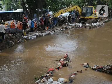 Petugas gabungan saat penanganan tanggul Kalibaru yang jebol di Simpang Hek, Kramatjati, Jakarta Timur, Senin (25/3/2024). (merdeka.com/Imam Buhori)