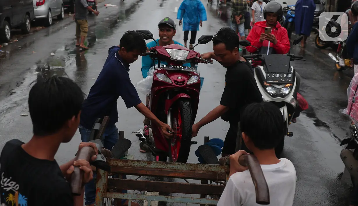 Warga mengangkut sepeda motor menggunakan gerobak melintasi banjir di jalan KH Hasyim Ashari, Kota Tangerang, Banten, Sabtu (16/7/2022). Warga sekitar membantu para pengendara yang melintas agar tidak terkena banjir dengan menawarkan jasa gerobak. (Liputan6.com/Angga Yuniar)