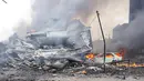 Bagian ekor pesawat Hercules C-130 hangus di tengah rumah rusak dan mobil di kawasan perumahan Medan, Selasa (30/6/2015). Diperkirakan sekitar 50 penumpang berada dalam pesawat untuk melakukan rotasi tugas piket. (AFP PHOTO/Muhammad Zulfan Dalimunthe)
