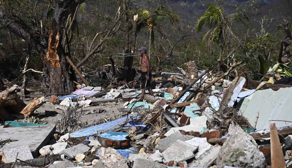 Seorang pria berjalan di tengah puing-puing rumah yang rusak akibat Badai Melissa di desa Boca de Dos Rios, provinsi Santiago de Cuba, Kuba pada Kamis 30 Oktober 2025. Sehari sebelumnya, atau Selasa (28/10/2025), badai ini menghantam Jamaika sebagai badai Kategori 5 yang sangat kuat. (YAMIL LAGE/AFP)