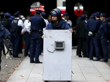 Petugas Polisi membawa alat penjinak bom di kuil Yasukuni di Tokyo, Jepang, (23/11). Ledakan bom terdengar jelas di kamar mandi umum Kuil Yasukuni yang membuat sebagian ruangan rusak. (REUTERS/Toru Hanai)