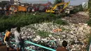Warga melihat alat berat beroperasi mengangkut sampah yang menutupi aliran sungai di Kali Baru, Bojonggede, Bogor, Minggu (28/4/2019). Dinas Lingkungan Hidup (DLH) Kabupaten Bogor mengerahkan 50 truk sampah untuk membersihkan sampah yang terbawa banjir dua hari lalu. (merdeka.com/Arie Basuki)