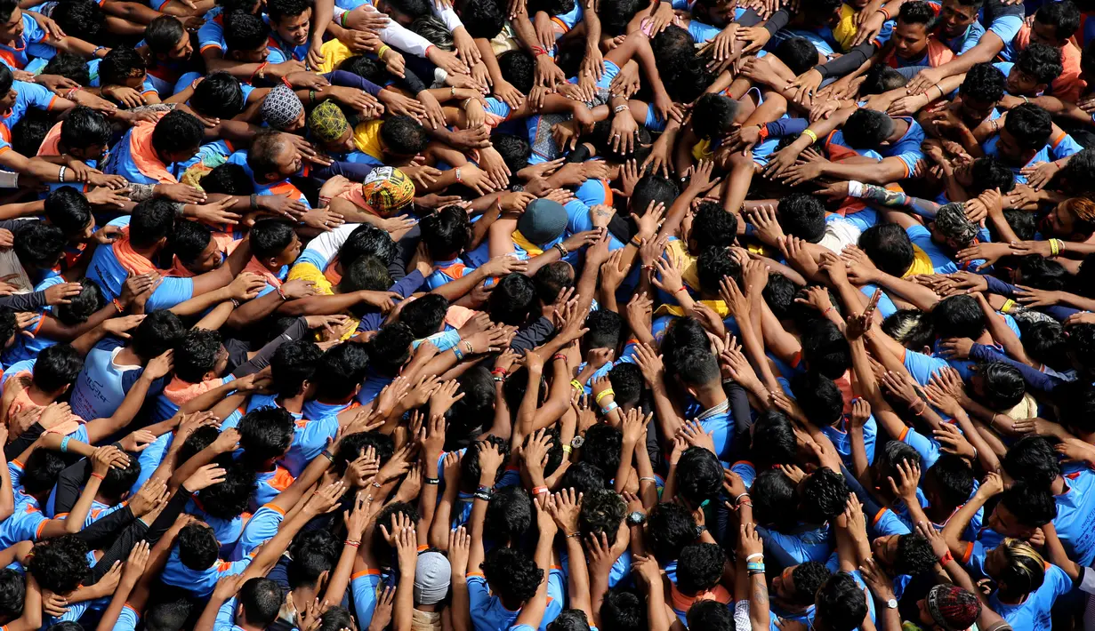 Pemuda India membentuk piramida manusia dalam perayaan Festival Janmashtami di Mumbai, Senin (3/9). Piramida manusia itu dibentuk untuk memecahkan pot berisikan susu yang menggantung di langit-langit rumah supaya bisa diambil isinya. (AP/Rafiq Maqbool)