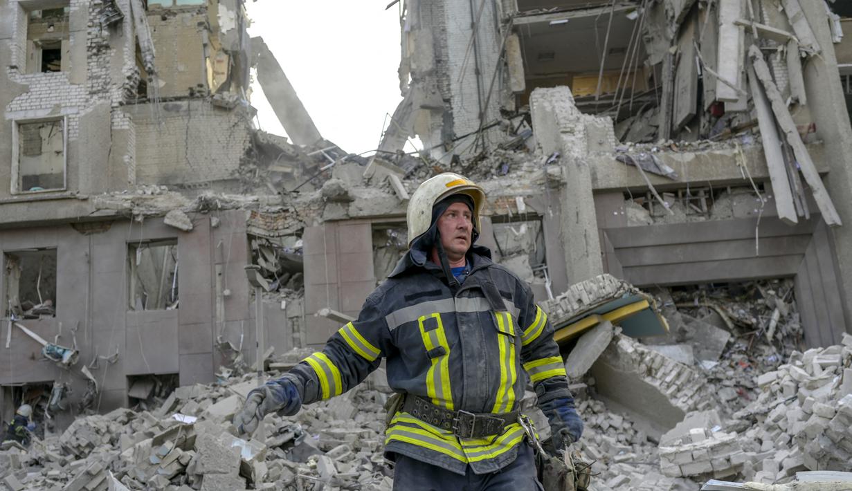 Petugas pemadam kebakaran membersihkan puing-puing gedung pemerintah yang terkena roket Rusia di Mykolaiv (29/3/2022). Serangan Rusia menghancurkan gedung pemerintah daerah di kota Mykolaiv, Ukraina selatan, pelabuhan utama yang diserang selama berminggu-minggu. (AFP/Bulent Kilic)